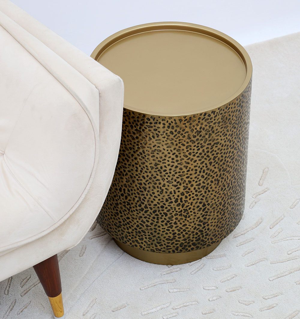 Cylindrical iron side table with a golden finish, serving as a functional accent table in contemporary home decor.