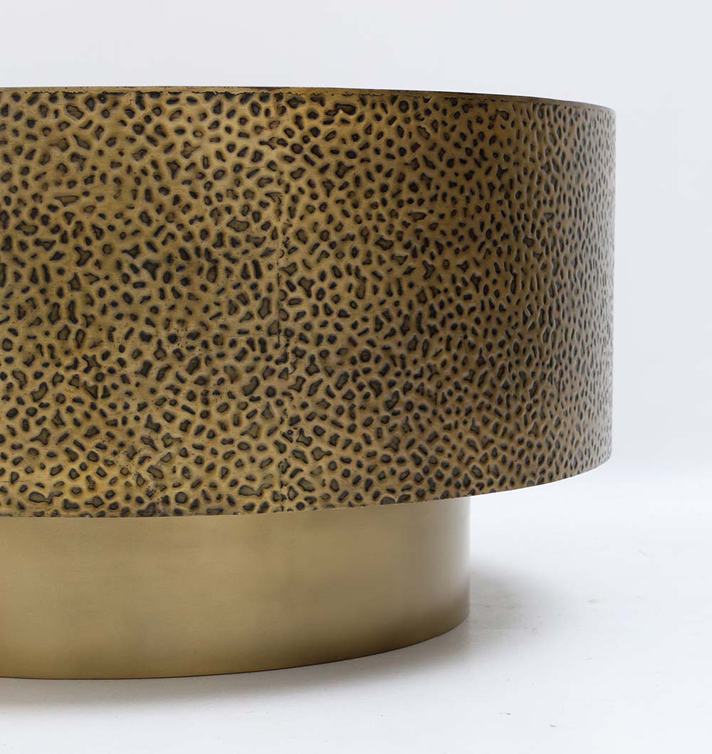 Refined round side table in golden metal with a bold textured design.