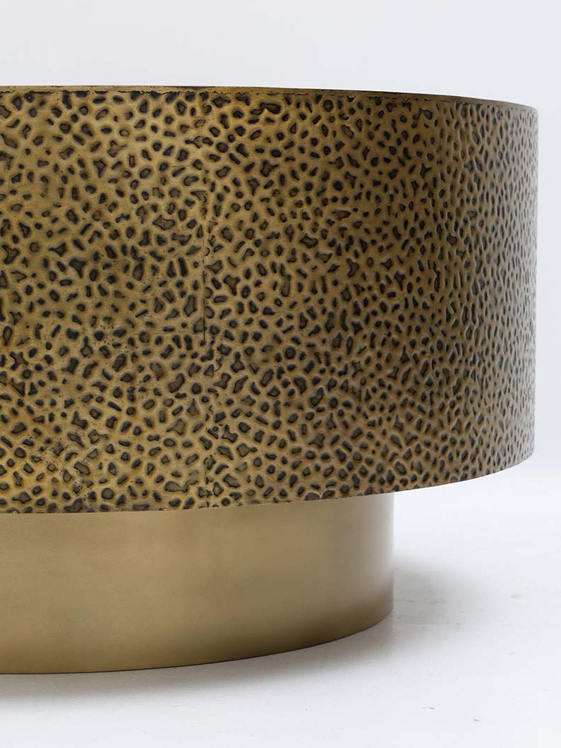Refined round side table in golden metal with a bold textured design.