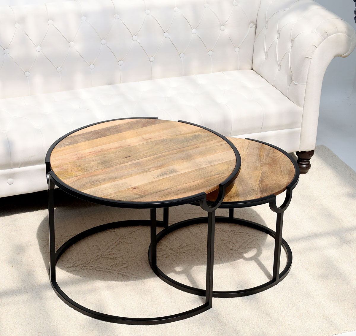 Modern nesting coffee table set with round wooden tops and sleek metal frames.
