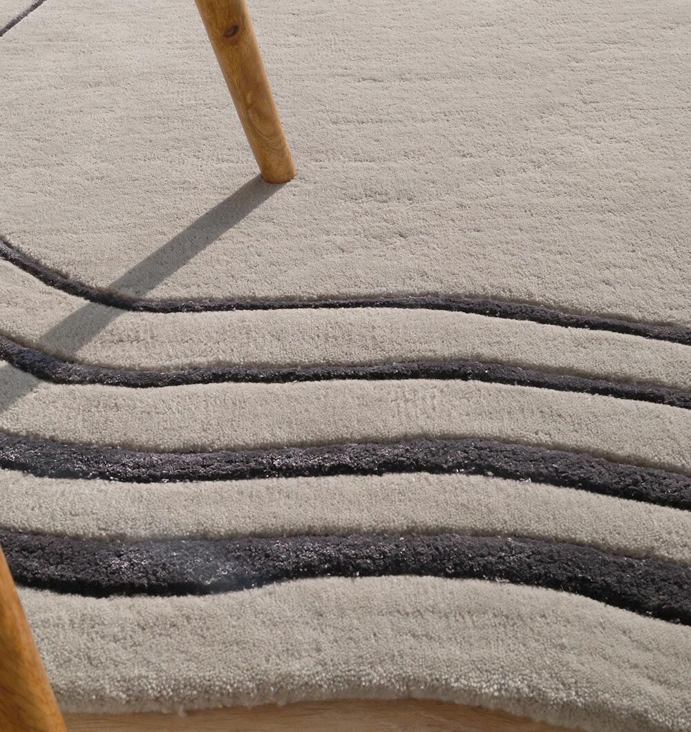 Close-up of the irregular rug's surface, highlighting the blend of black and grey fiber for a stylish, textural contrast.