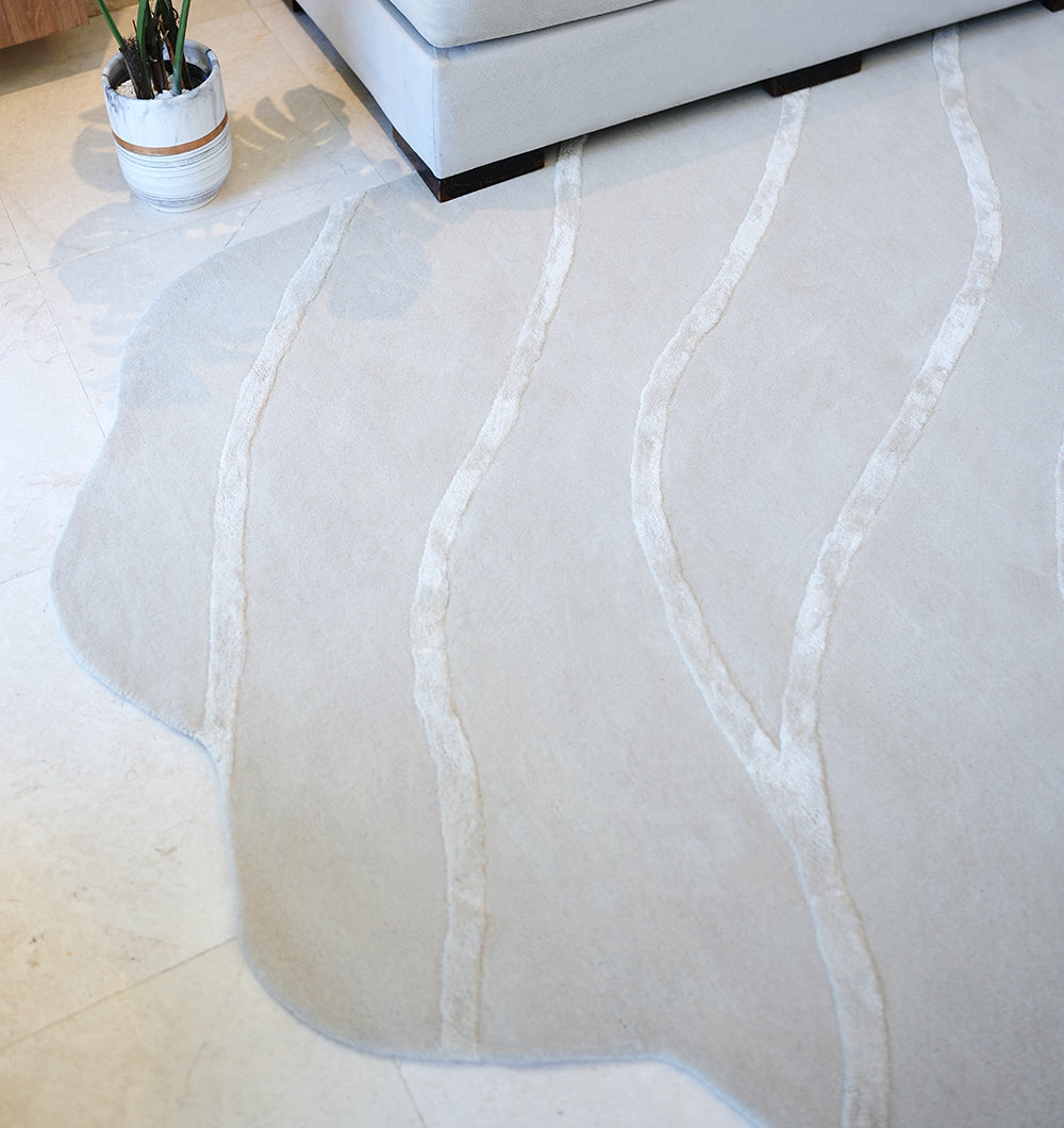 Handmade irregular rug anchoring a bedroom setting, highlighting its practical durability and luxurious texture underfoot.