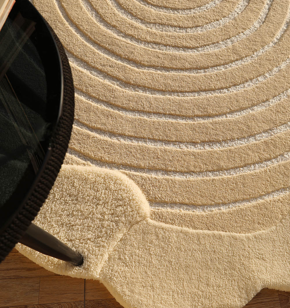 Close-up detailing the luxurious texture underfoot of the beige-colored shaped round handmade rug.