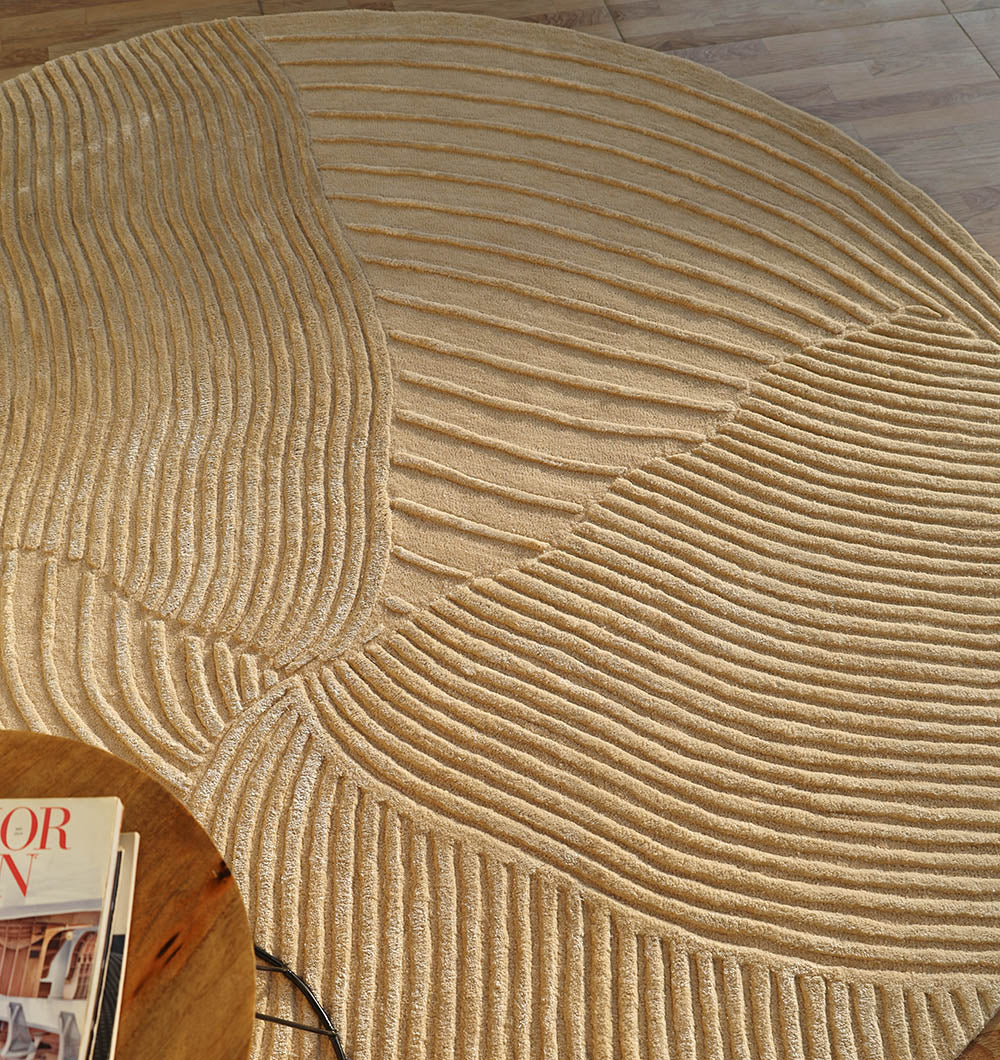 Top-down view of the round beige handmade rug, showcasing the full shape and aesthetic sophistication.