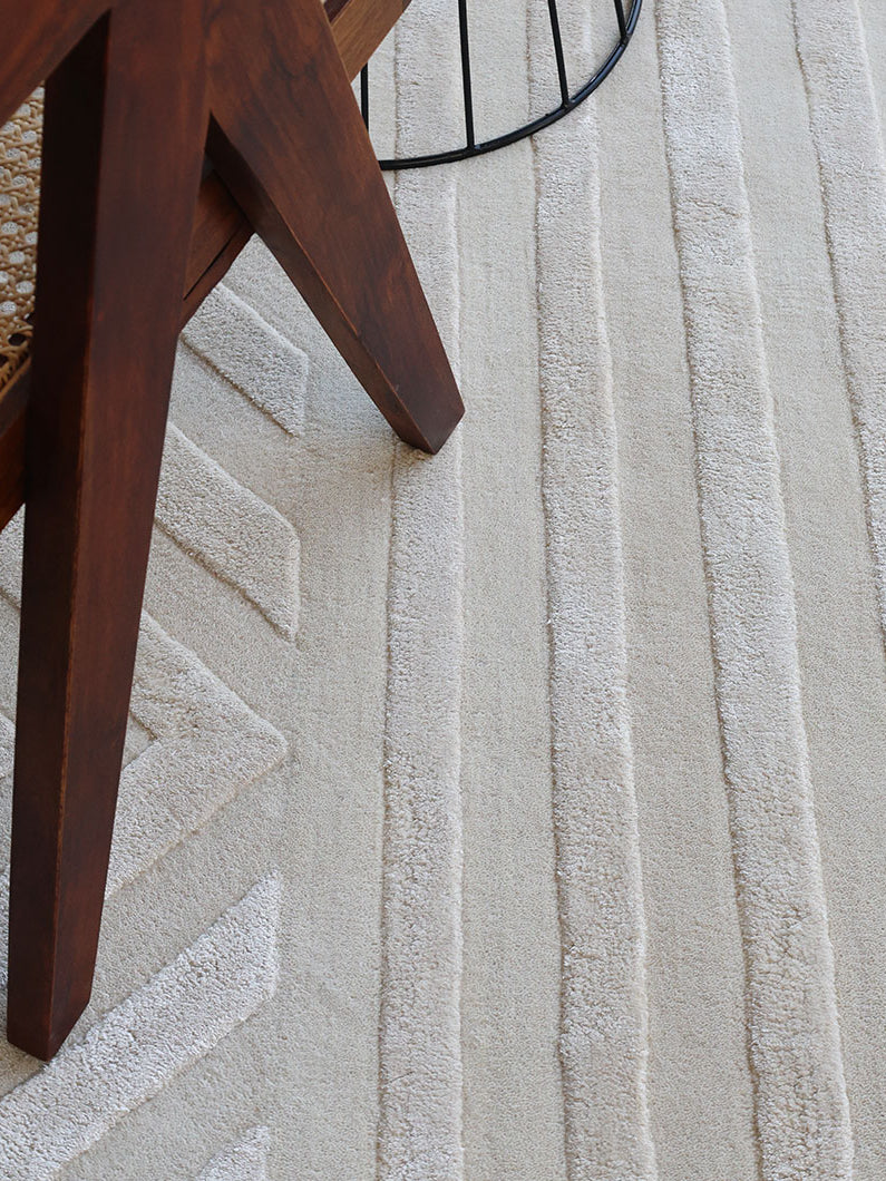 Close-up of the modern linear pattern on the natural white rug, highlighting its aesthetic sophistication next to wood flooring.