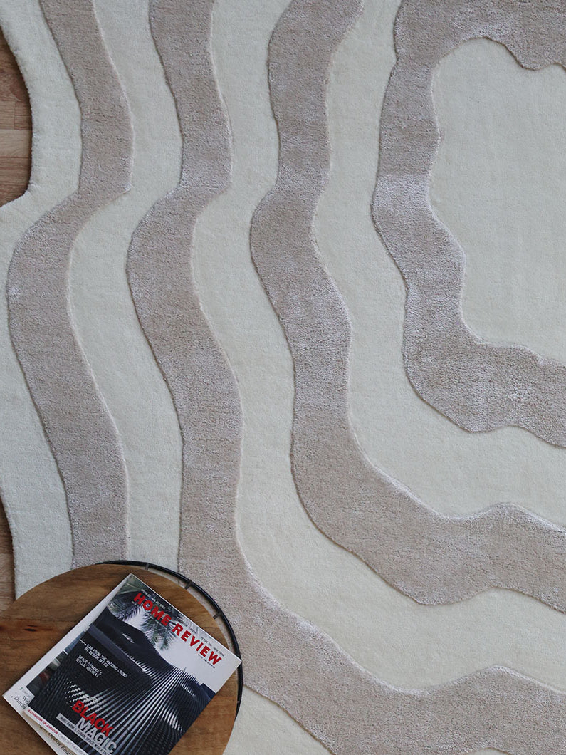 Close-up detailing the luxurious texture underfoot of the beige and cream rug, emphasizing the high-viscose blend for superior softness.