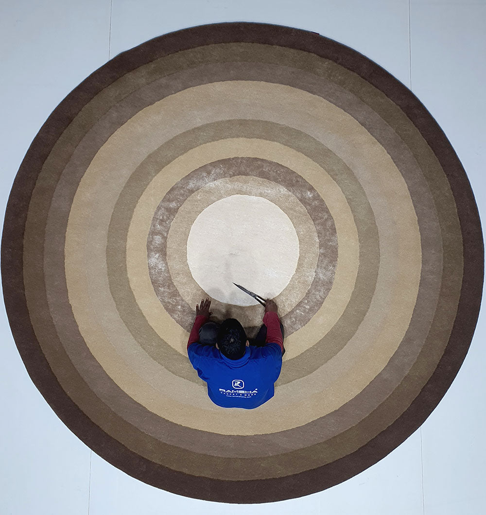 Top-down view showing the finishing work on the edge of the circular rug, detailing the craftsmanship applied to the final border.