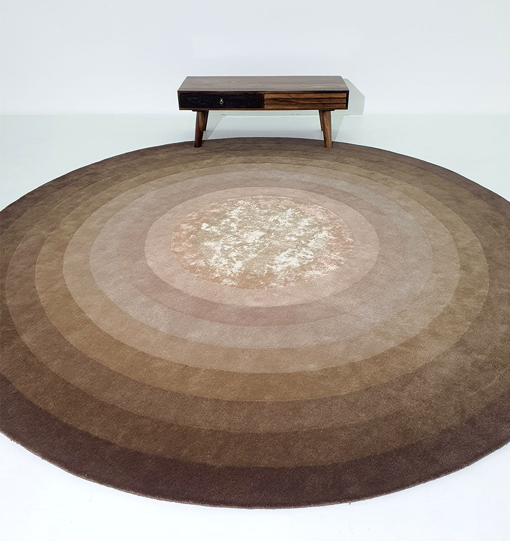 Oversized round rug placed in a dining room, emphasizing the resilient wool and durable weave for heavy use.