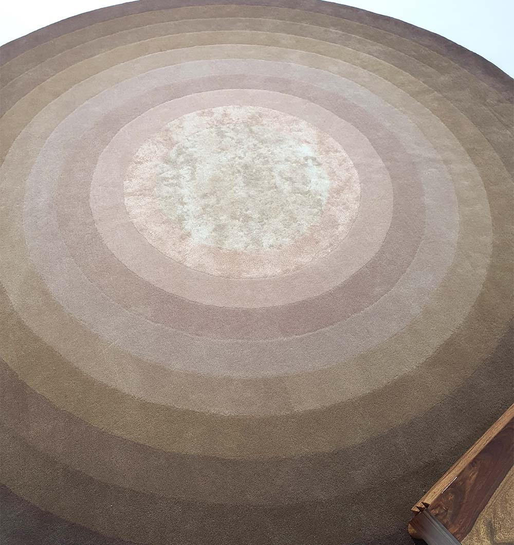 Full view of the large round rug anchoring an open floor plan, acting as a contemporary accent and elegant centerpiece.