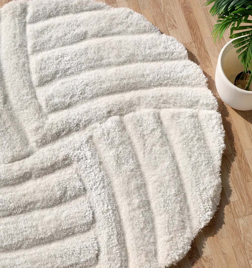 Angled view of the handmade round white/cream rug, designed to seamlessly blend into versatile home decor.