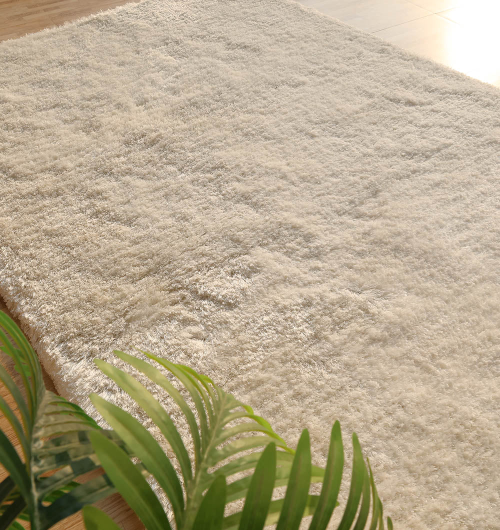 Side angle of the rectangular area rug, showcasing the full thickness and height of the plush shaggy fibers.