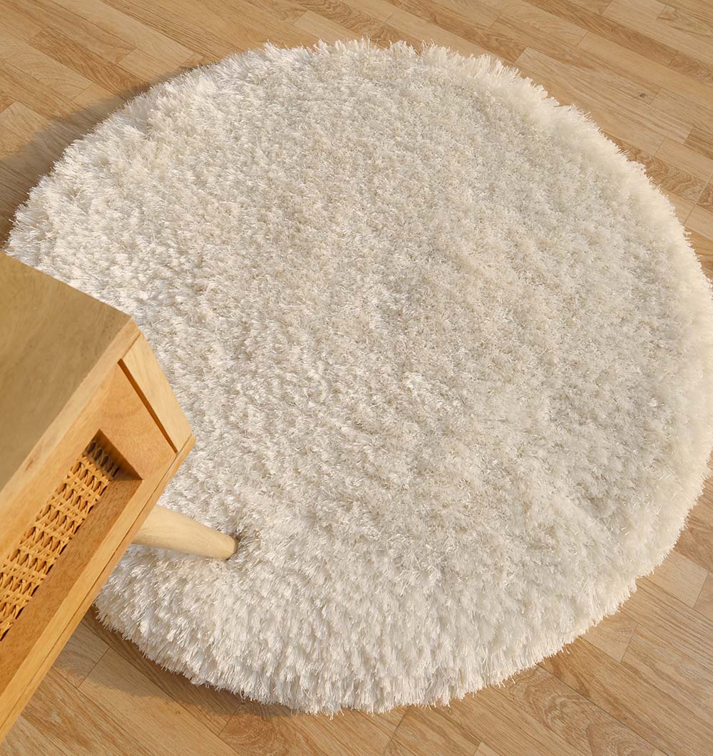 Top-down view of the white round shaggy rug anchoring a living space, adding warmth and plush texture to the home decor.