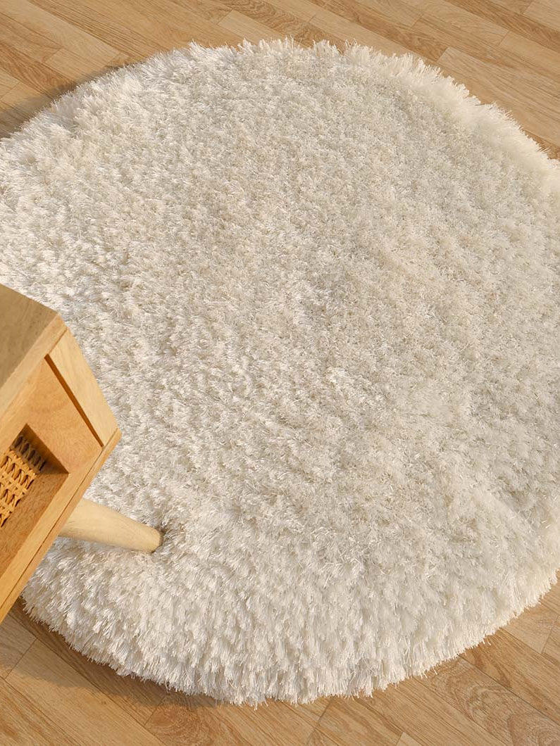 Top-down view of the white round shaggy rug anchoring a living space, adding warmth and plush texture to the home decor.