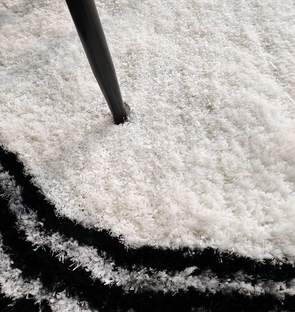 Black and white shaggy rug placed in a living space, adding warmth, comfort, and a touch of sophistication to the room.