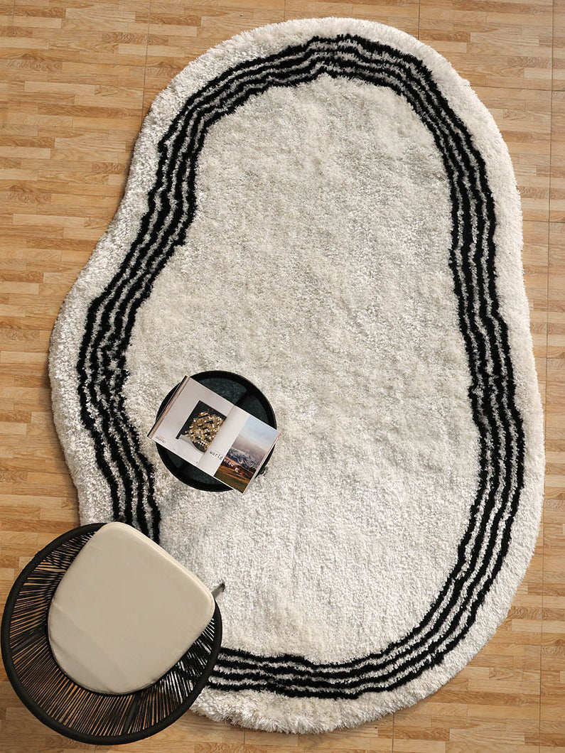 Handmade shaggy rug in black and white irregular shape, offering comfort and plush texture for the floor.
