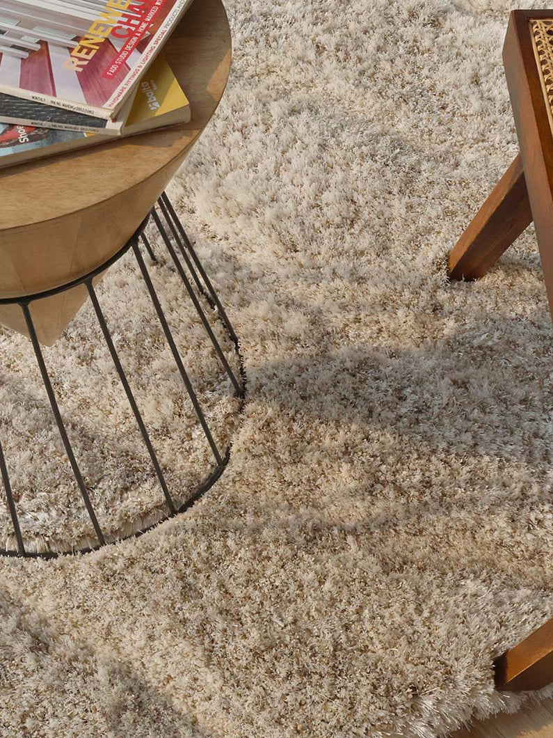 Close-up of the beige spiral-shaped rug next to a decorative element, showcasing its sophisticated design and superior softness.