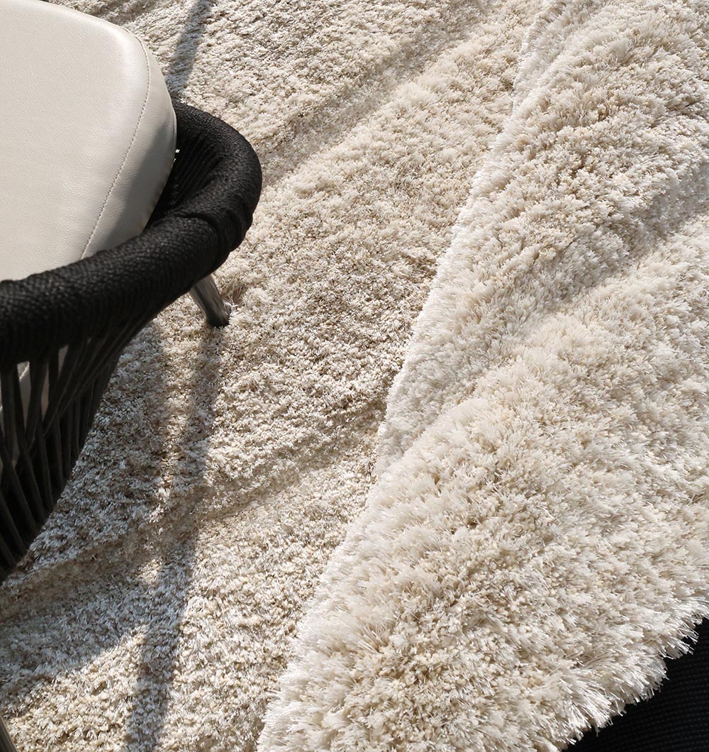 Close-up detailing the plush texture and softness of the handmade beige shaggy rug, made from the 80% polyester blend.