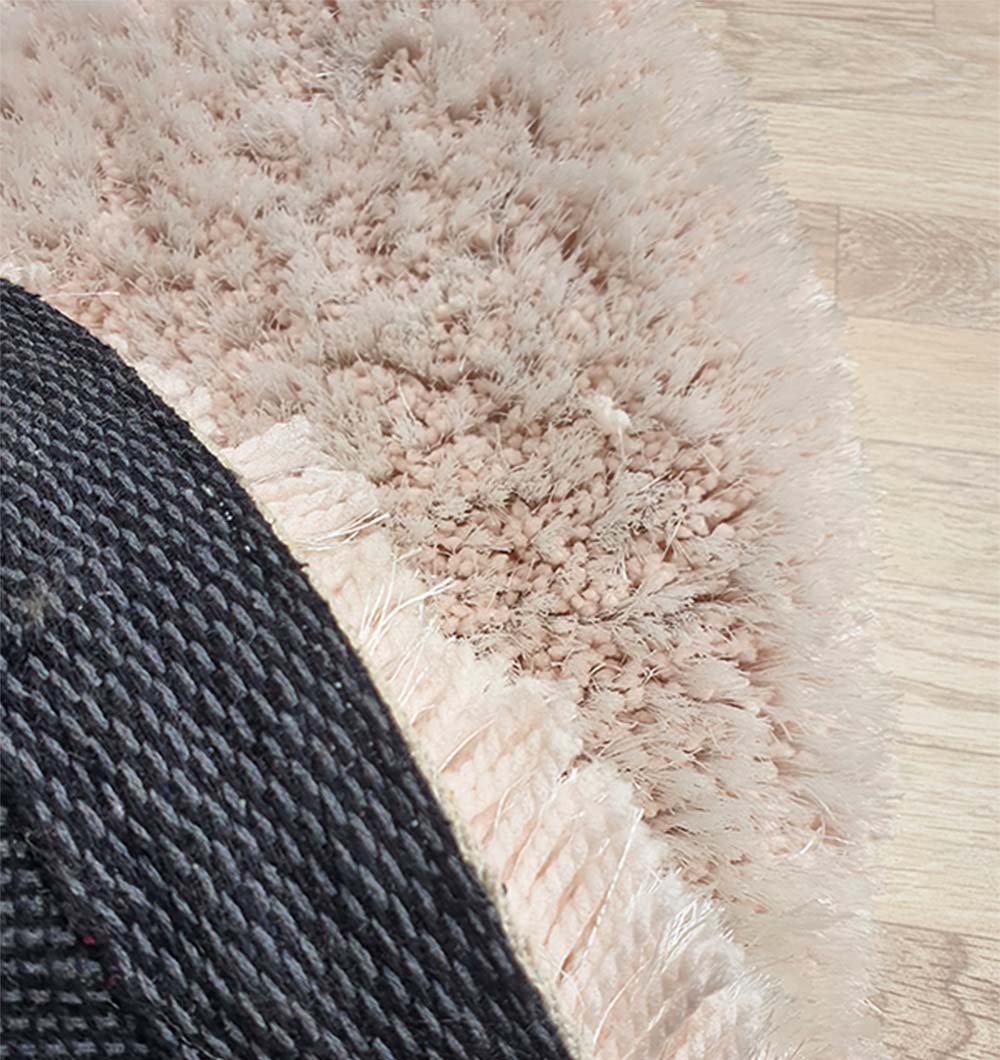 Backside of the circular beige shaggy rug, confirming the solid weave and hand-tufted construction.