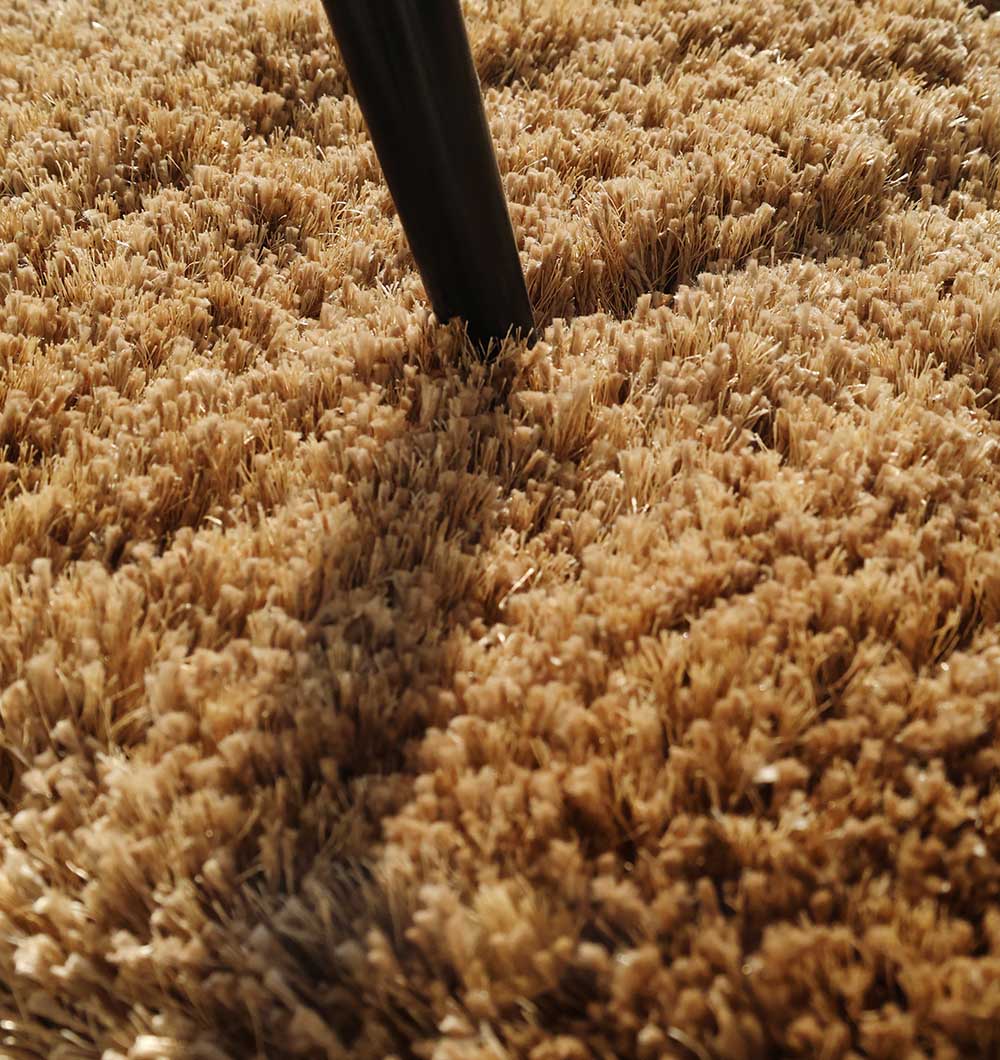 Close-up of the irregular brown shaggy rug, clearly showing the thick plush texture and handmade construction.