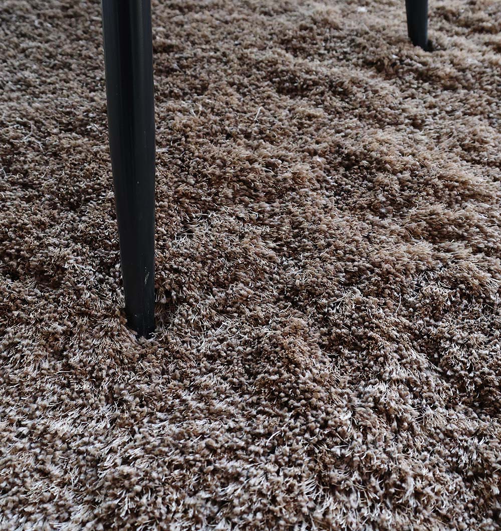 Detailed close-up of the rug's fibers, emphasizing the expert craftsmanship and comfort of the plush shaggy pile.