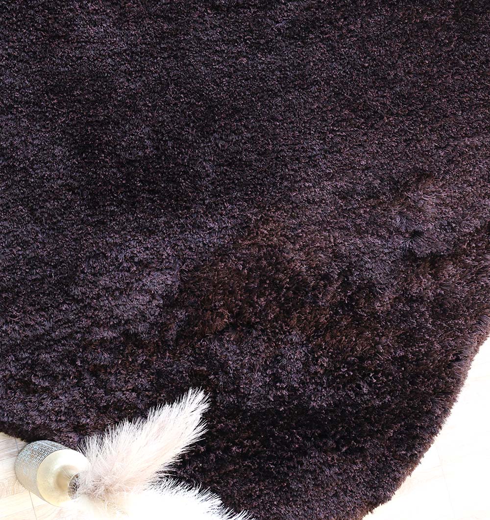 Close-up of the irregular dark brown shaggy rug, showcasing its unique design and modern sophistication.