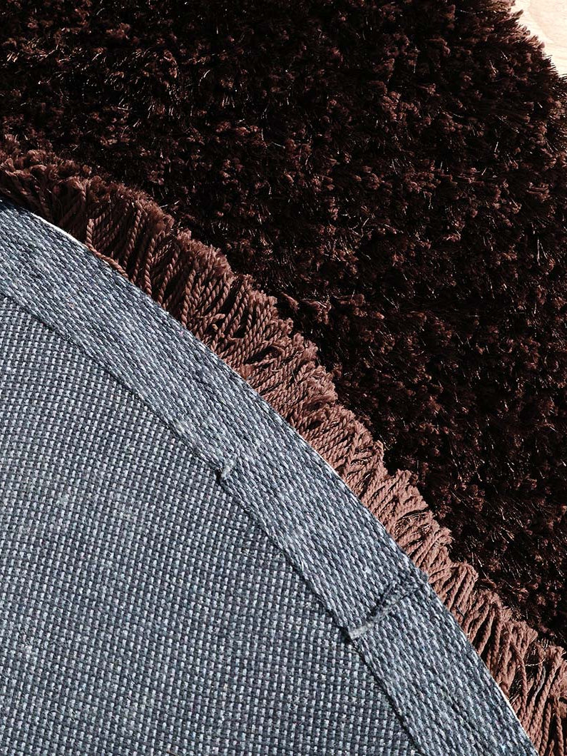 Backside of the dark brown round shaggy rug, confirming the expert handmade construction and durable backing.