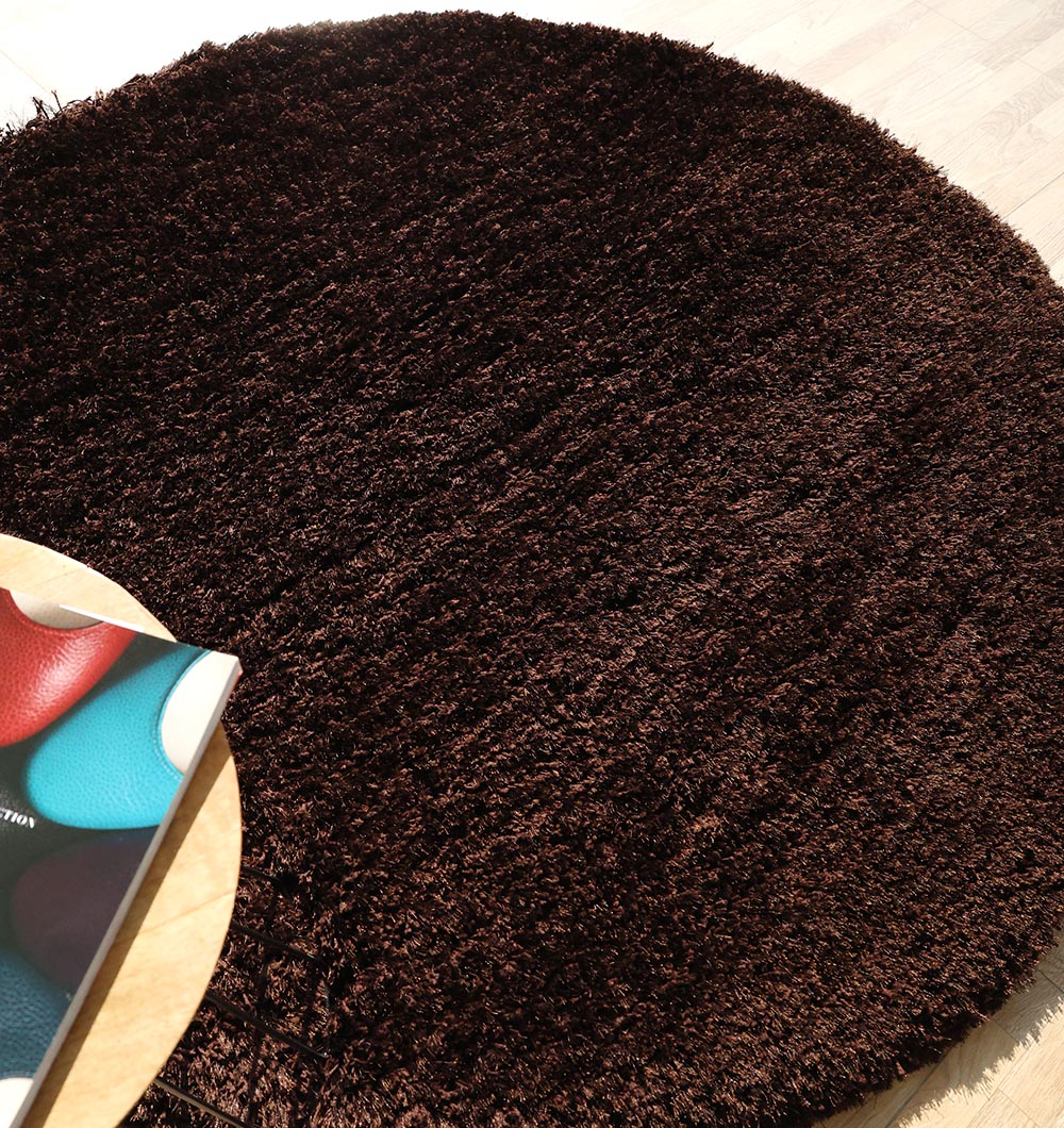Side close-up highlighting the thick shaggy pile height and softness of the round dark brown carpet.