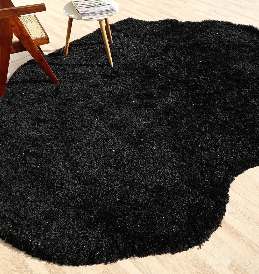 Top-down view of the irregular black shaggy rug anchoring the living area, adding modern sophistication to the home decor.
