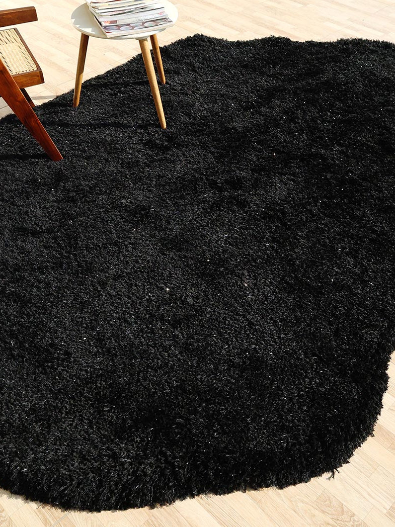 Top-down view of the irregular black shaggy rug anchoring the living area, adding modern sophistication to the home decor.