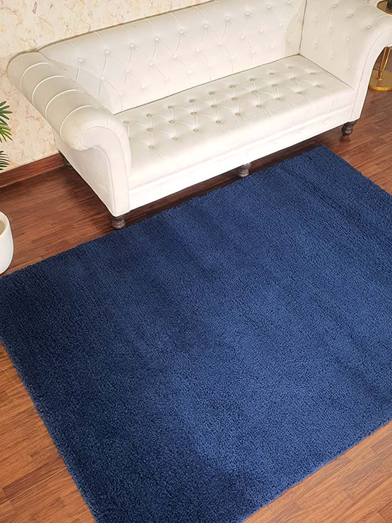Navy blue handmade shaggy rug placed in a livingroom setting, adding a touch of luxury and warmth to the home decor.