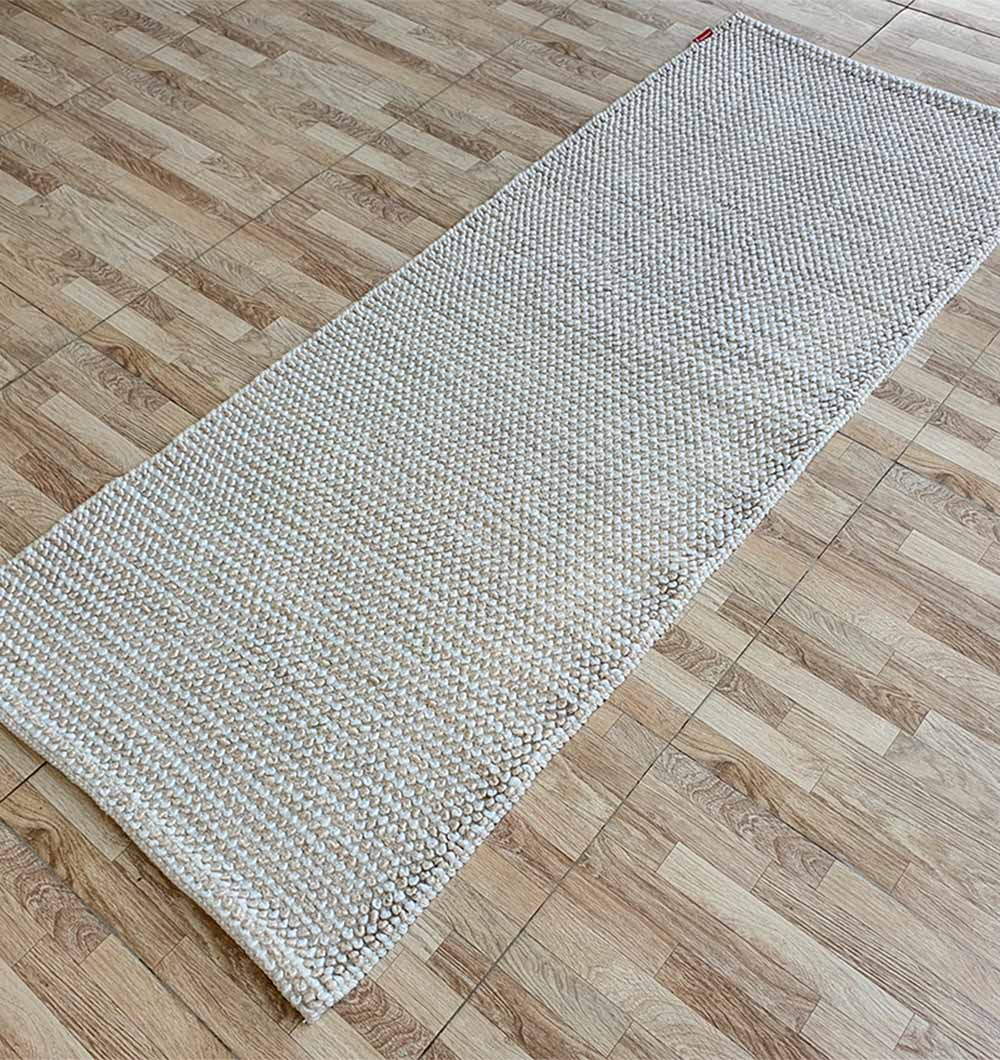 Side angle of the natural white woven runner rug, showcasing the tight weave and high durability of the $100\%$ polyester fiber.