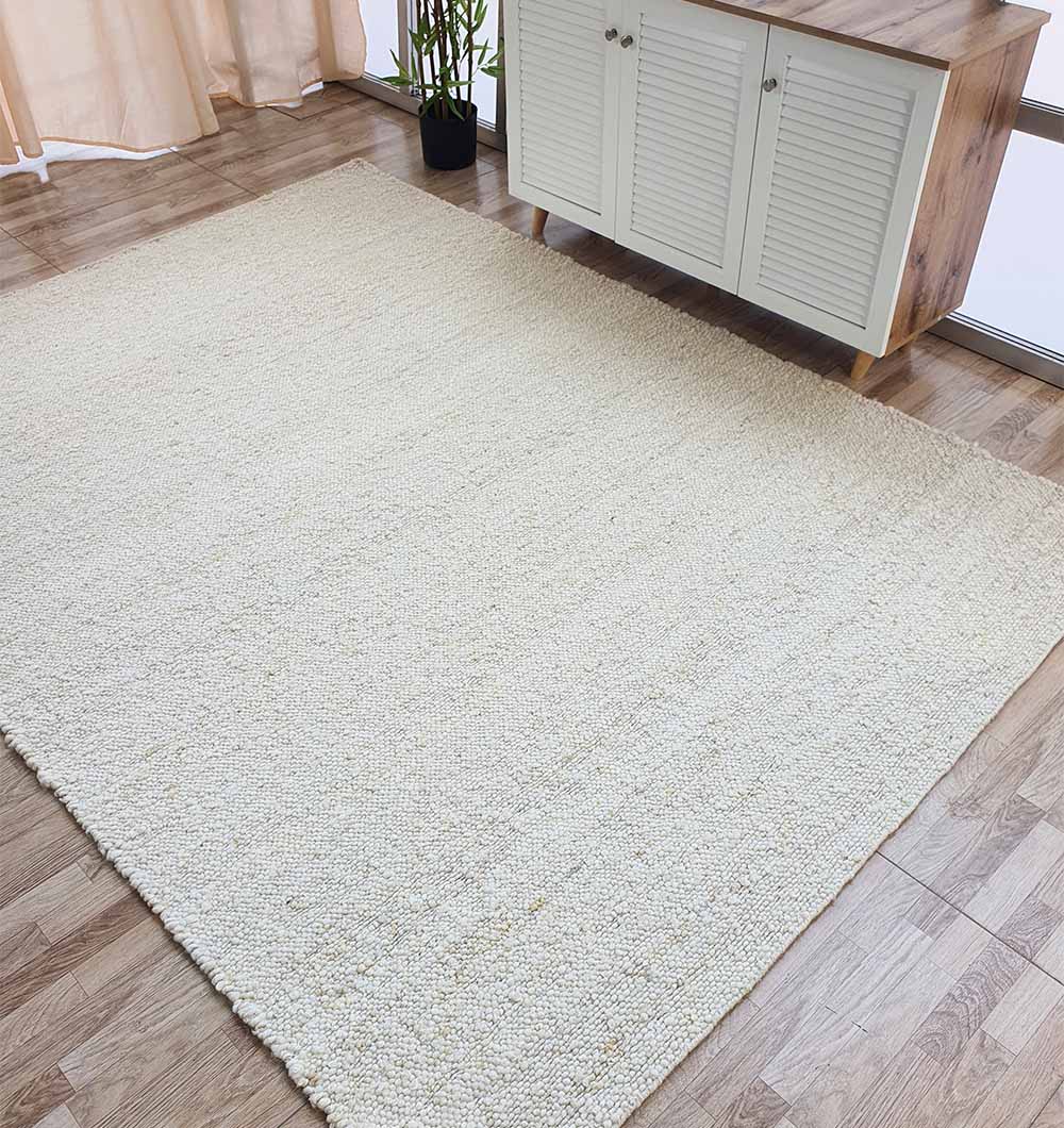 Handmade rectangle natural off-white woven rug anchoring a living space, adding warmth and comfort to home decor.